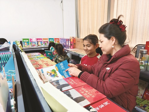 店員買合木提汗·司地克向?qū)W生介紹圖書